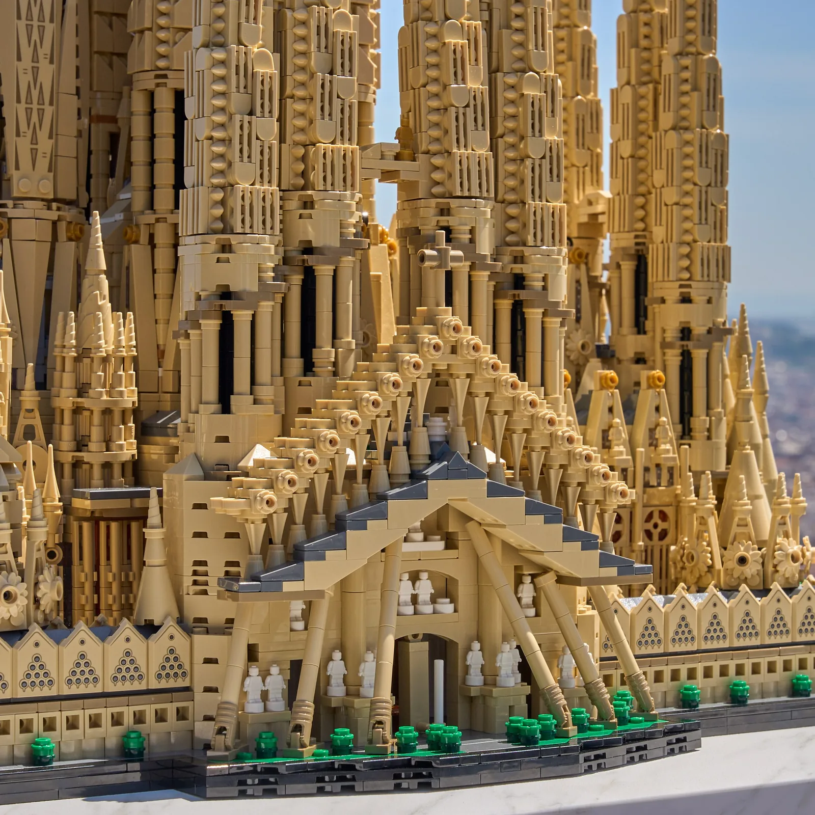 Détail rapproché de la maquette LEGO Architecture Sagrada Família 21065, gros plan sur la façade de la Nativité avec ses ornements sculptés, ses pinacles et ses sapins en briques vertes au pied du portail, recréation précise du chantier de la basilique de Barcelone construite depuis 1882