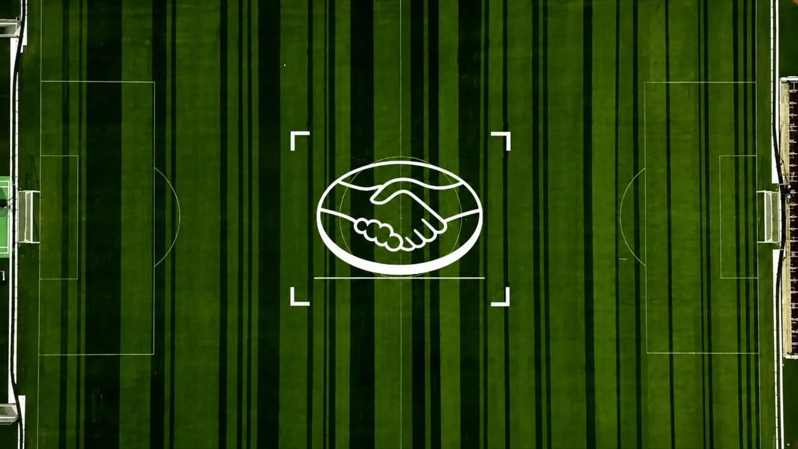 Vue aérienne du Mercado Livre Arena Pacaembu à São Paulo dévoilée par GUT São Paulo le 22 juin 2026, pelouse verte en tonte alternée formant le motif d'un immense code-barres, lignes vert sombre et vert clair de différentes épaisseurs traversant tout le terrain dans le sens de la longueur, illustration centrale d'une poignée de mains blanche dessinée au sol au centre du terrain dans un cadre photographique