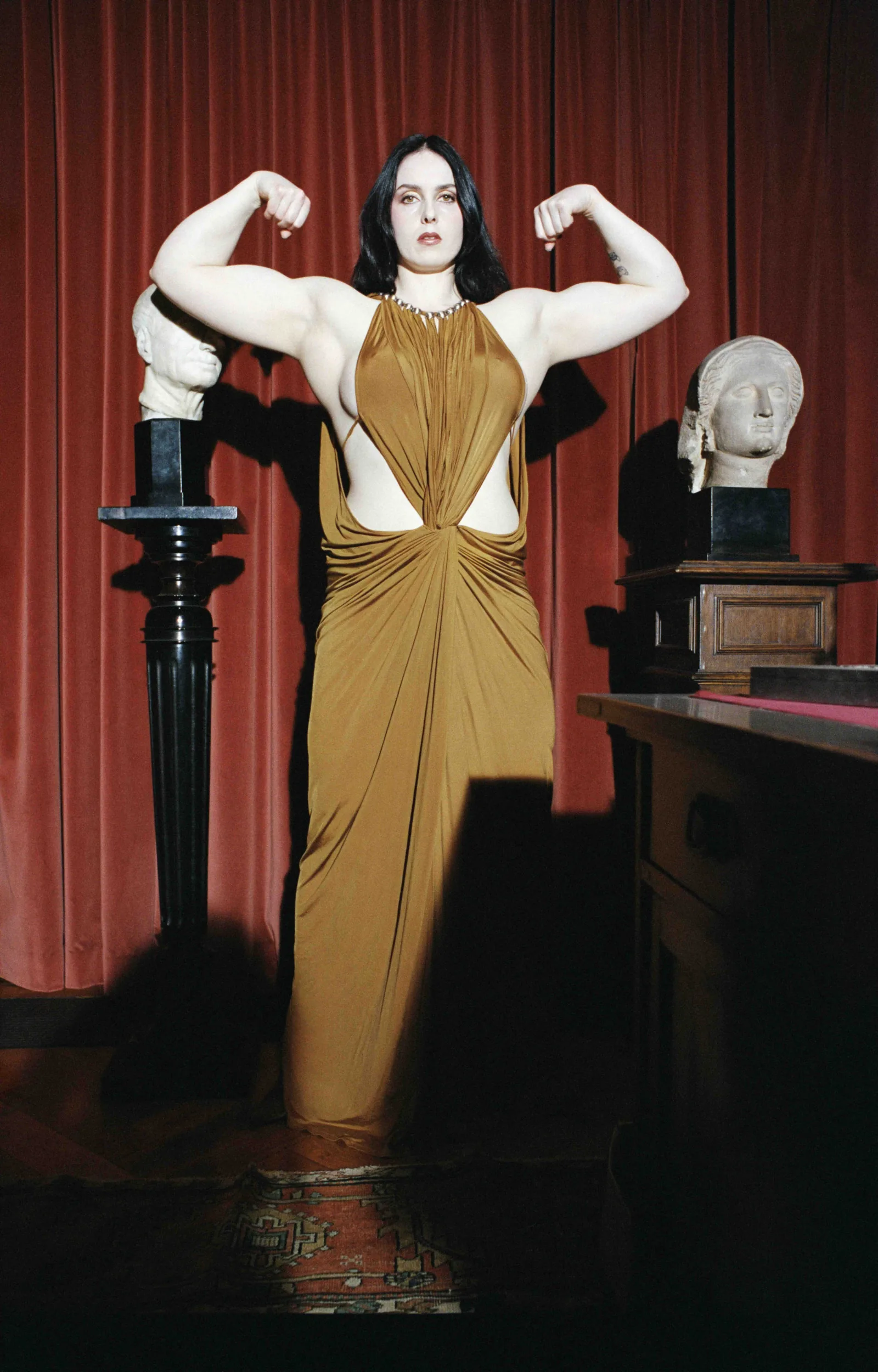 Photographie de Camille Vivier choisie comme visuel d'ouverture de sa première rétrospective à la Maison Européenne de la Photographie du 10 juin au 13 septembre 2026, portrait de la bodybuildeuse Deborah en robe asymétrique dorée posant dans le bureau d'étude de Sigmund Freud à Londres